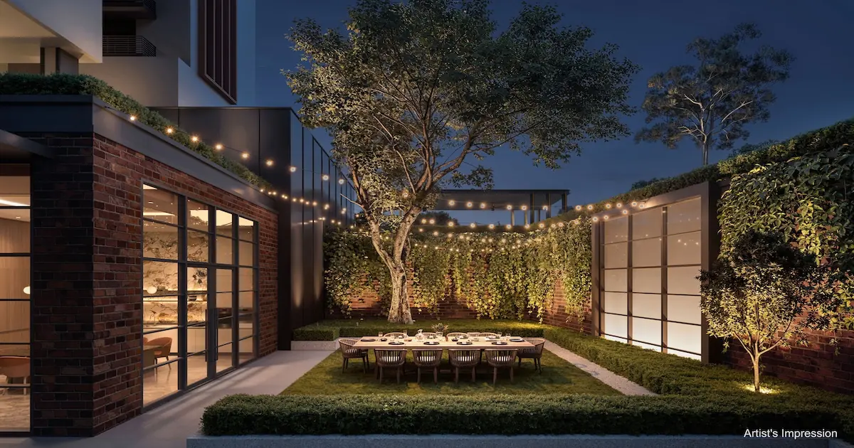 Hudson Place Residences courtyard garden with alfresco dining table beneath a heritage tree and string lights at dusk.