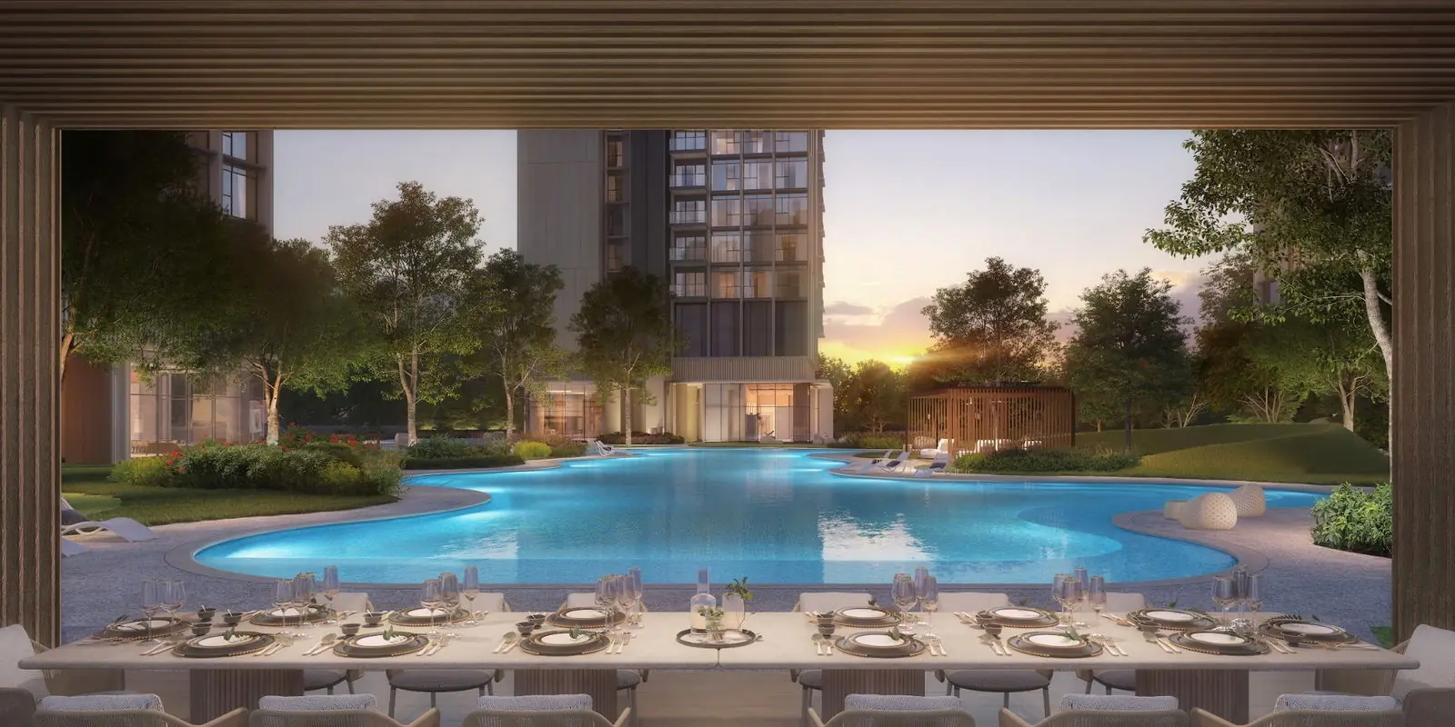 View from an outdoor dining pavilion featuring a set table, looking across the illuminated lagoon pool towards a residential tower at Nava Grove during dusk.